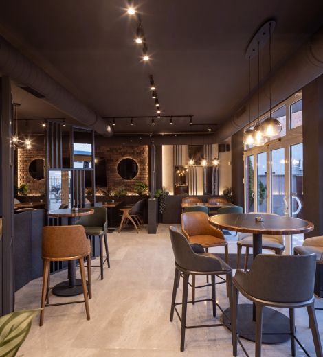 Restaurant interior with mixed leather seating, round tables, and pendant lighting.