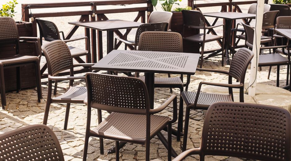 Outdoor patio with perforated metal tables and chairs at a restaurant.